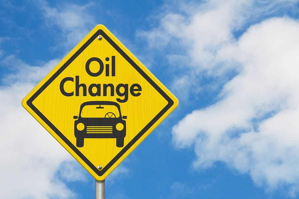 oil change with car on yellow warning highway road sign